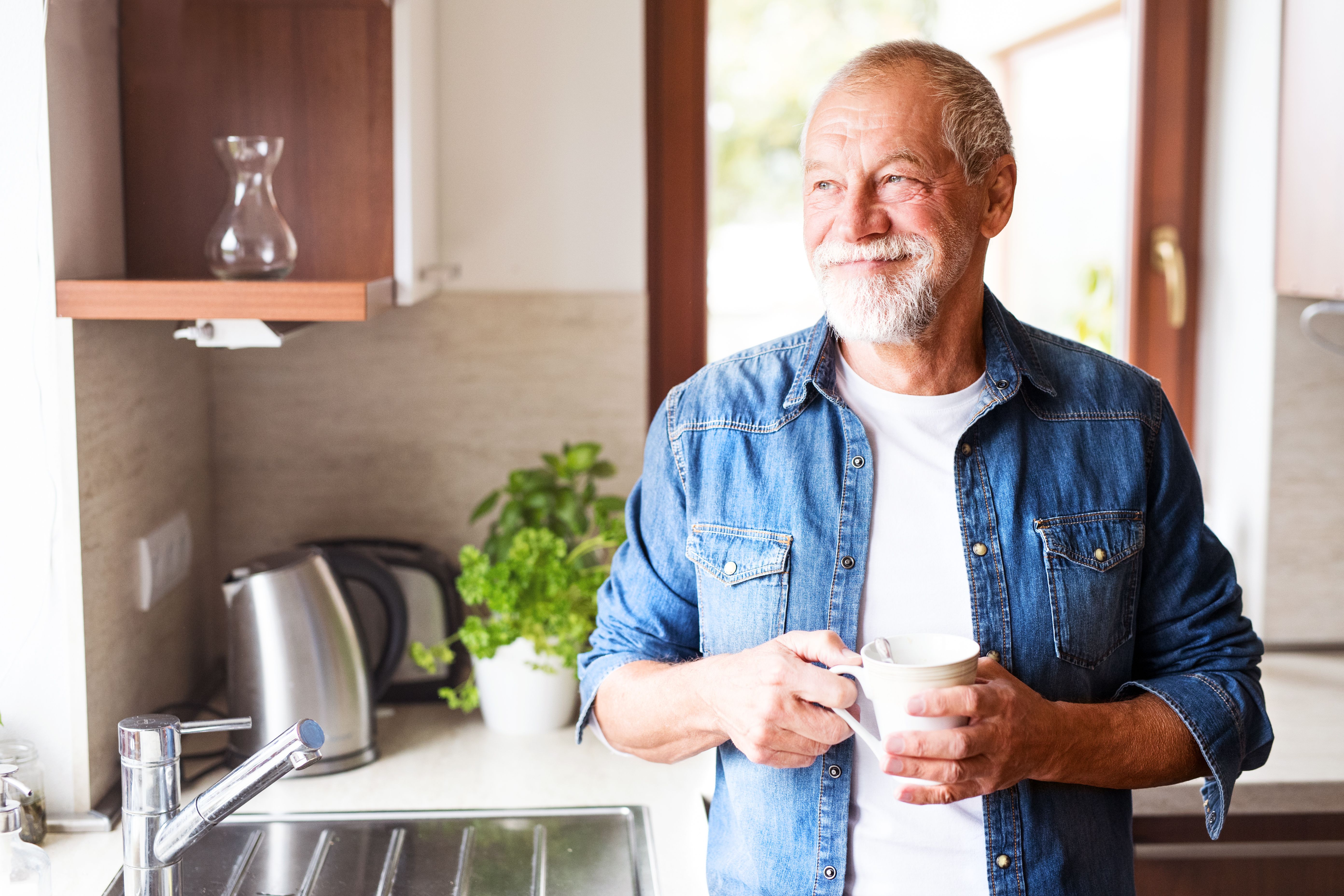 Smiling homeowner holding a mug in his kitchen